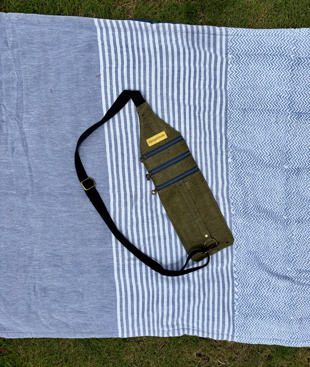 small, flat, green crossbody with 3 compartments and blue accents.