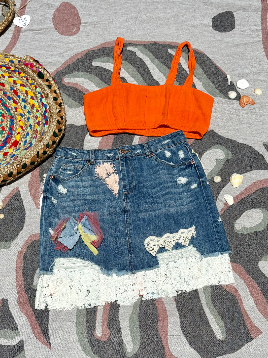 mid-length denim skirt with lace detailing, various colorful patches, and fringe of different fabrics down the back.