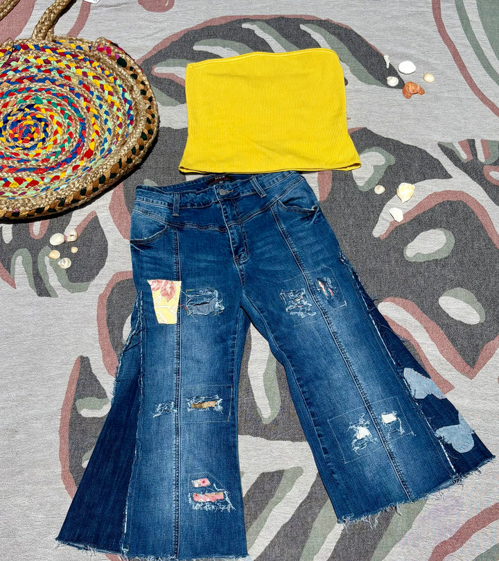 cropped and flared dark denim jeans with various colorful patchwork and butterfly shaped patches.