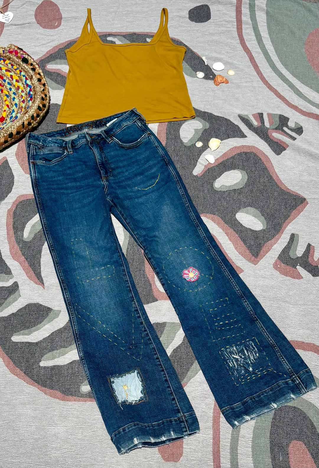 bootcut/flare dark denim jeans with yellow embroidery and various patchwork.