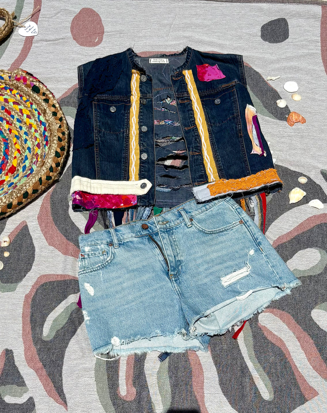 cropped, dark denim vest with colorful patchwork and long fringe off the back.
